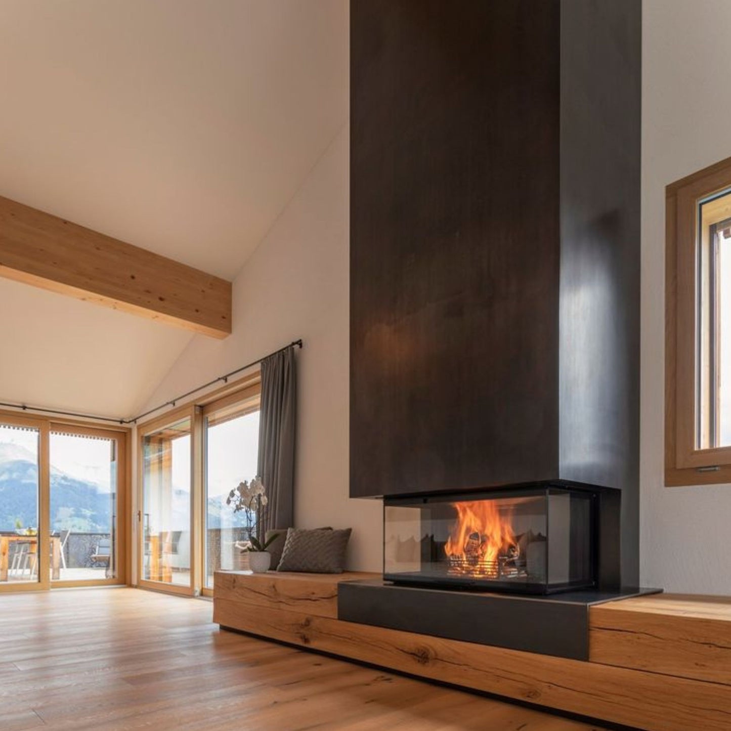 Toplozračni kamin z kaminskim vložkom z tristransko zasteklitvijo, obzidava je spodaj iz lesa, zgoraj pa v črni barvi