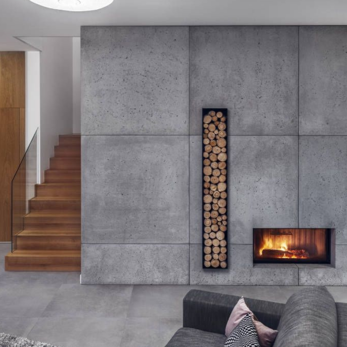 Obzidan kaminski vložek z ravno zasteklitvijo, obzidava je v celoti obložena z keramičnimi ploščicami v imitaciji betona, na levi strani kaminskiega vložka pa je niša za drva