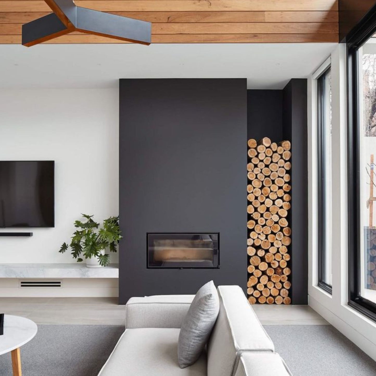 Zidan kamin, z obzidavo v črni barvi in nišo za drva na desni strani