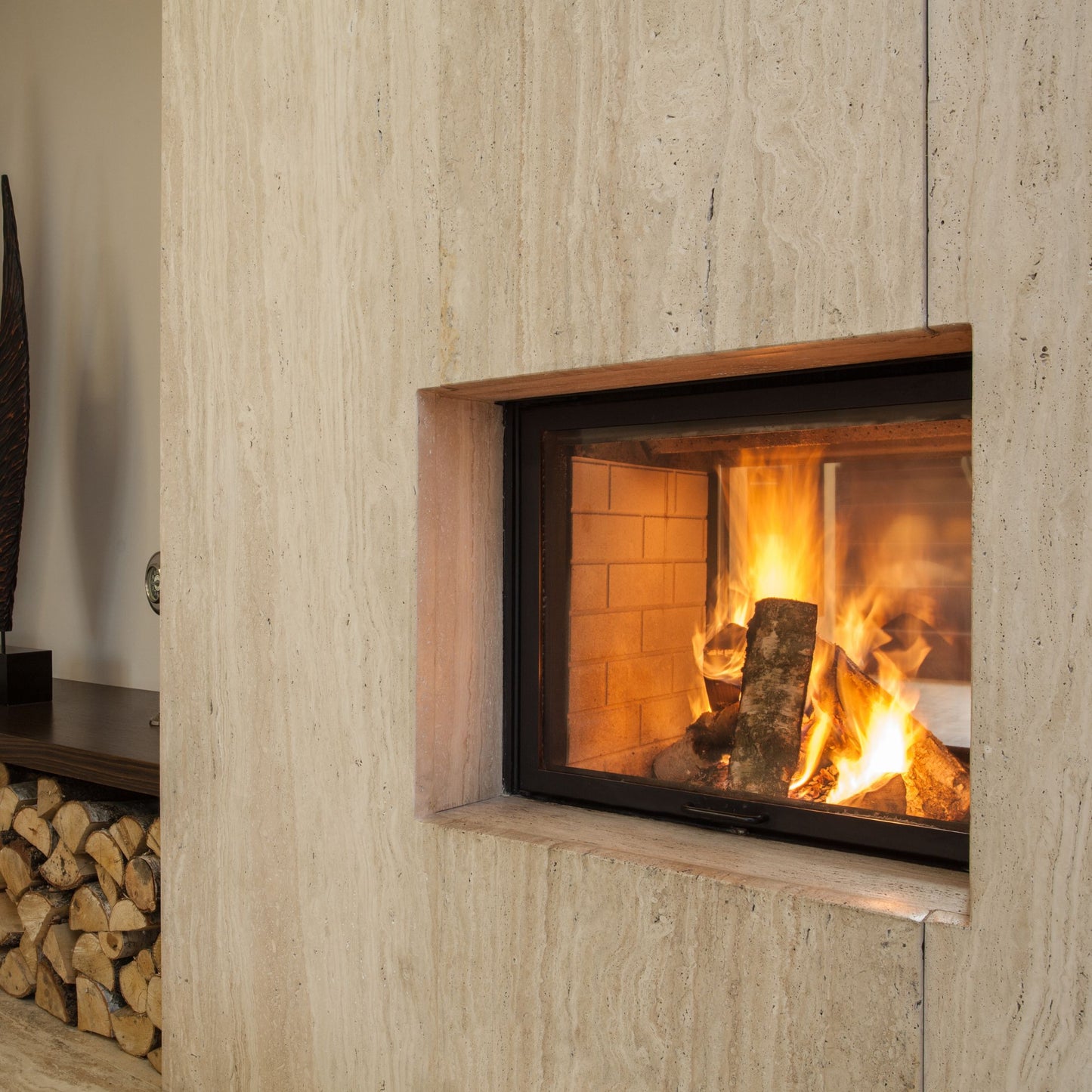 Obzidan kaminski vložek z ravno zasteklitvijo, obzidava je obložena z bež keramičnimi ploščicami