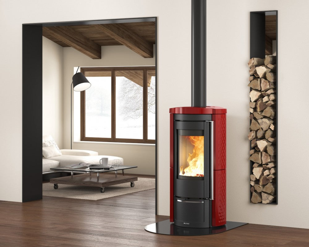 Red pellet stove in a modern living room with a mirror and stacked logs.